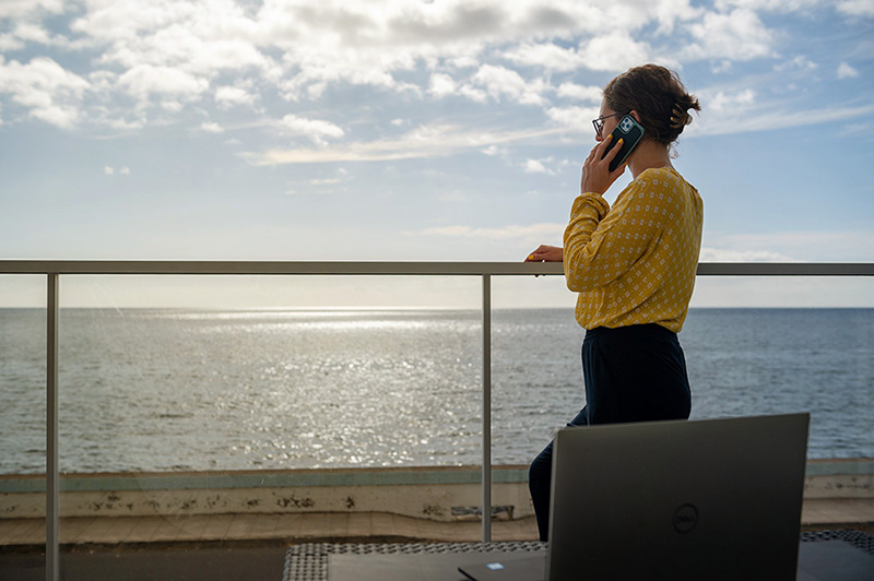Symbolbild Madeira-Workation: Frau telefoniert mit Blick aufs Meer