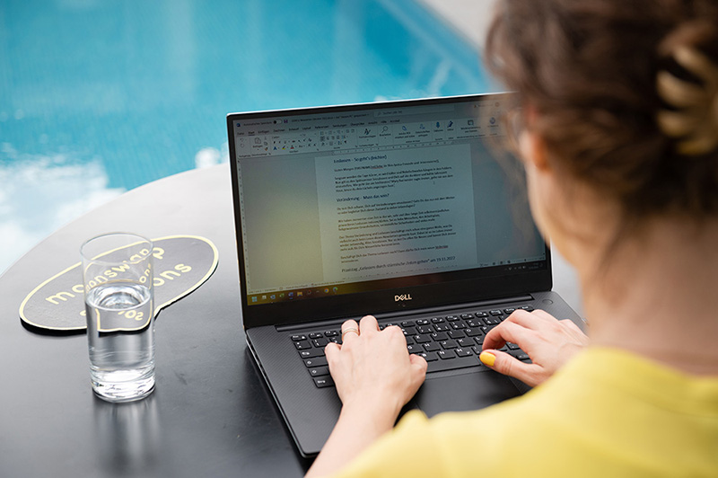 Symbolbild Workation-Anbieter: Frau arbeitet auf Workation am Pool